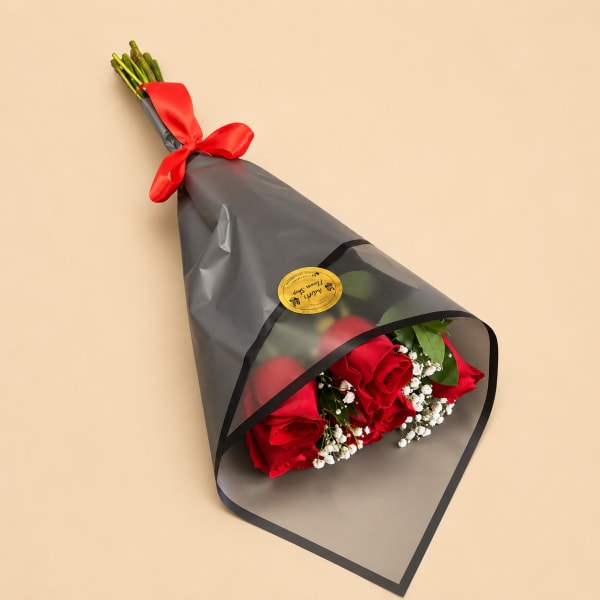 Bouquet of red roses wrapped in black paper with a red ribbon