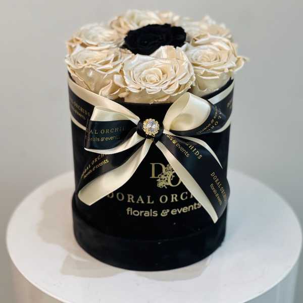 Black hatbox with cream roses and a black center rose, tied with ribbon
