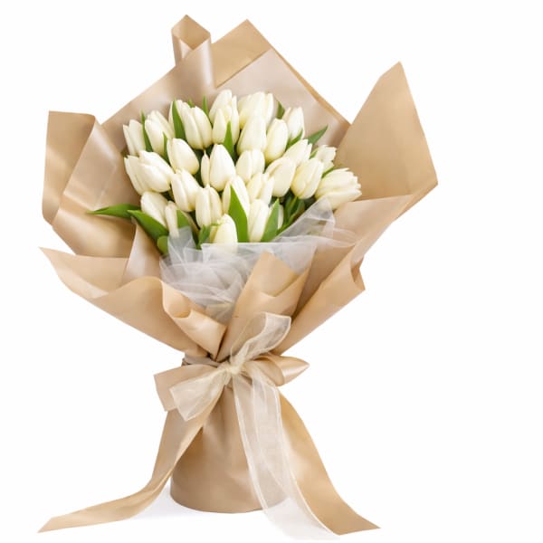 Bouquet of white tulips wrapped in tan paper with a ribbon