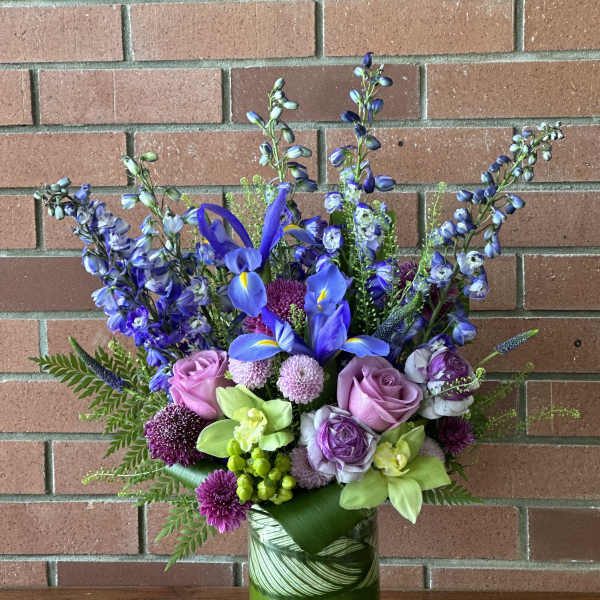Blue iris and purple flowers in a green glass vase