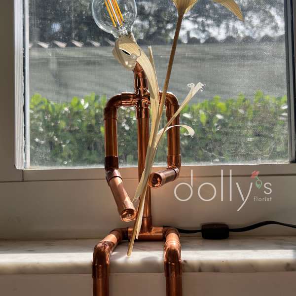 Copper pipe figure with a light bulb head and palm-like leaves