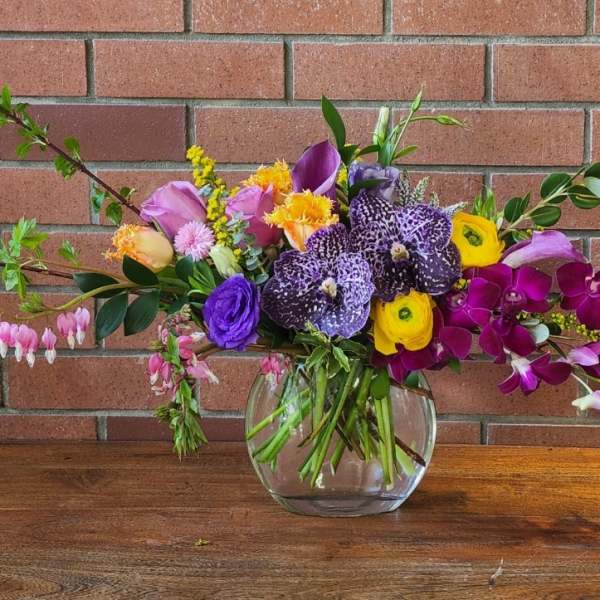 Mixed bouquet in a clear glass vase with purple, pink, and yellow flowers