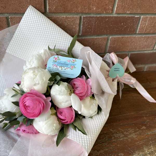 Bouquet of pink and white ranunculus wrapped in white paper
