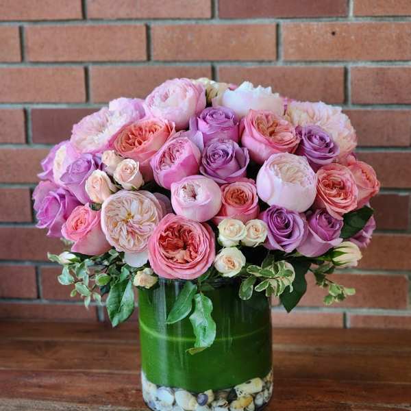 Pink and lavender roses arranged in a glass vase