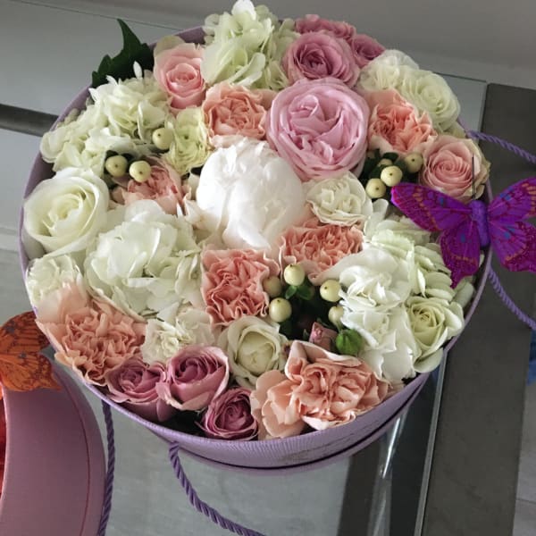 Round box of pink and white roses with carnations and a purple butterfly decoration