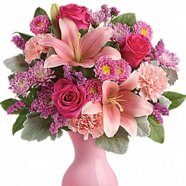 Pink floral bouquet in a pink vase with lilies and roses