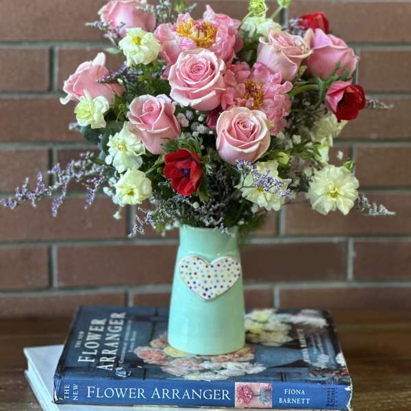 Pink roses and mixed flowers in a mint vase with a heart decoration