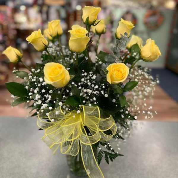 Yellow roses in a glass vase with baby's breath and a yellow ribbon bow