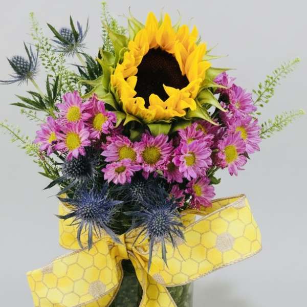Sunflower bouquet with pink daisies and blue thistle, tied with a yellow ribbon