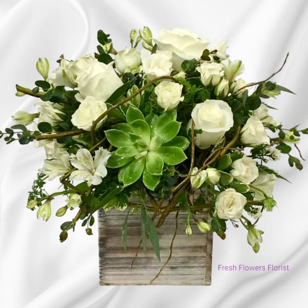 White roses and alstroemeria in a rustic square vase with a green succulent