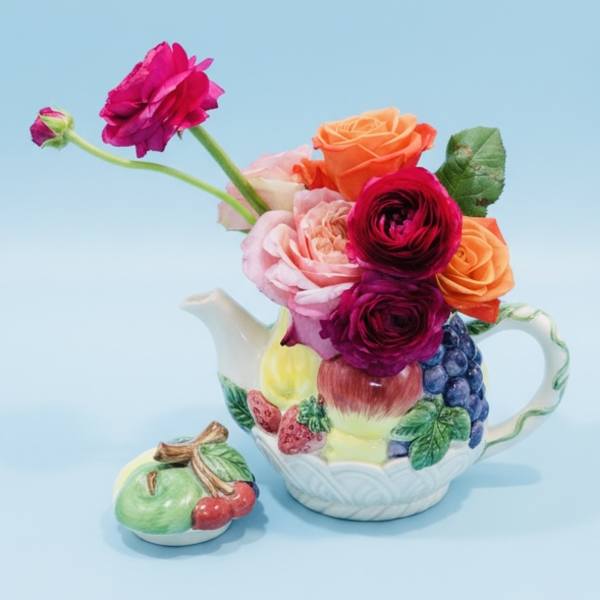 Colorful flowers arranged in a fruit-patterned teapot with a matching lid