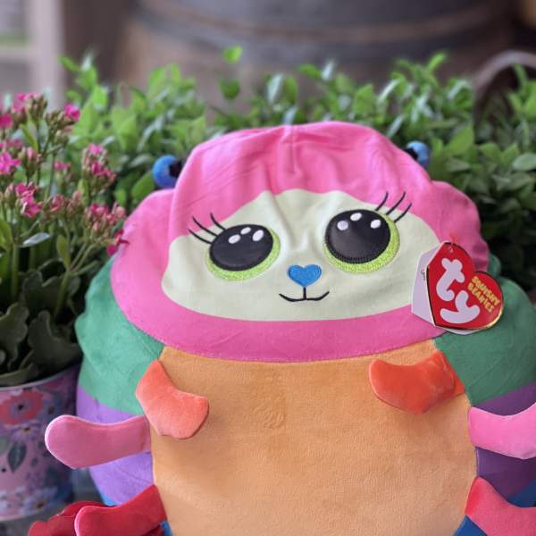 Plush toy with a red rose in front of potted flowers