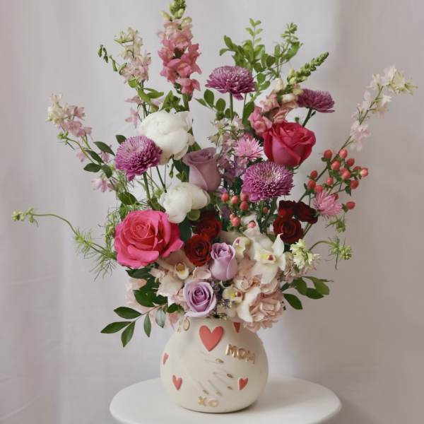Mixed pink and white flower arrangement in a cream vase with heart decorations