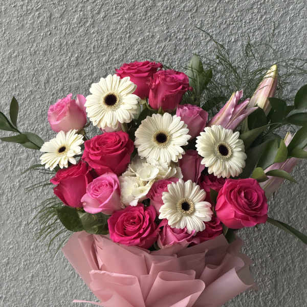 Bouquet of pink roses and white gerbera daisies wrapped in pink paper