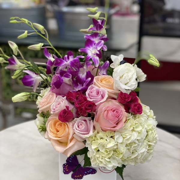 Mixed bouquet of roses, orchids, and hydrangeas in a white box