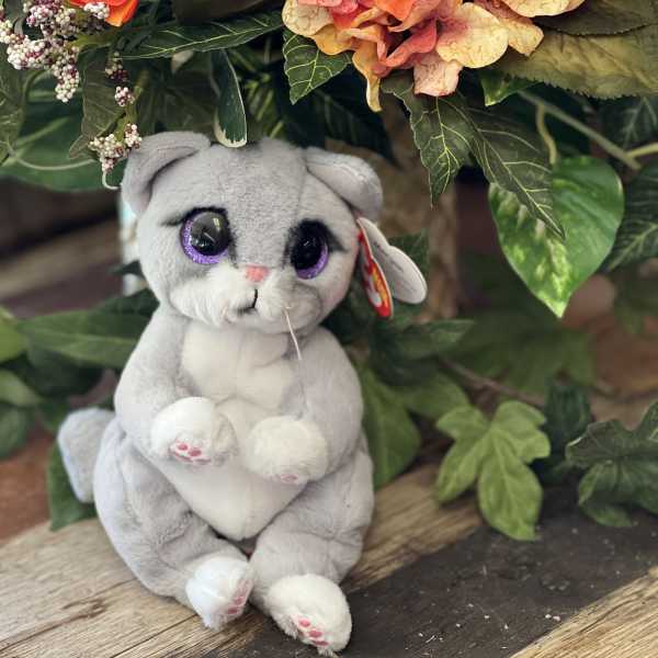 Plush gray cat toy sitting beneath orange and peach flowers