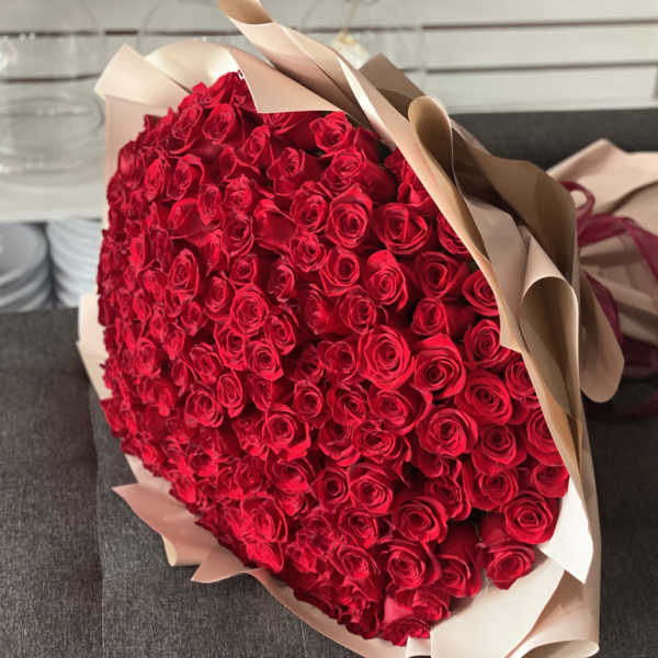 Large bouquet of red roses wrapped in beige paper