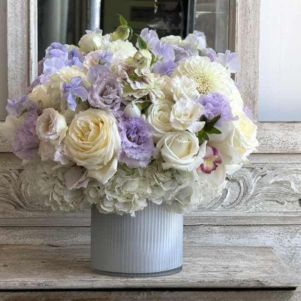 Pastel bouquet of white and lavender flowers in a ribbed vase