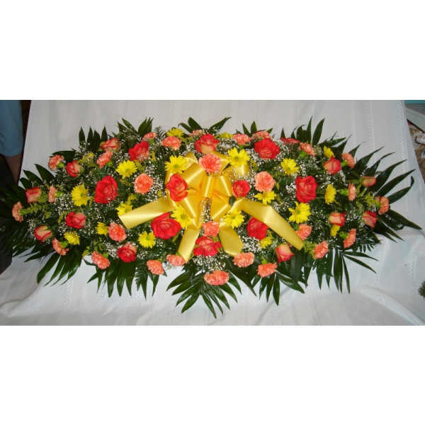 Oval floral spray with red roses, yellow daisies, and a gold ribbon bow