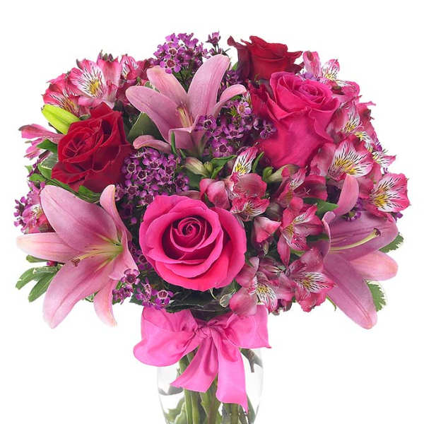 Pink and red bouquet of roses and lilies in a glass vase with a ribbon