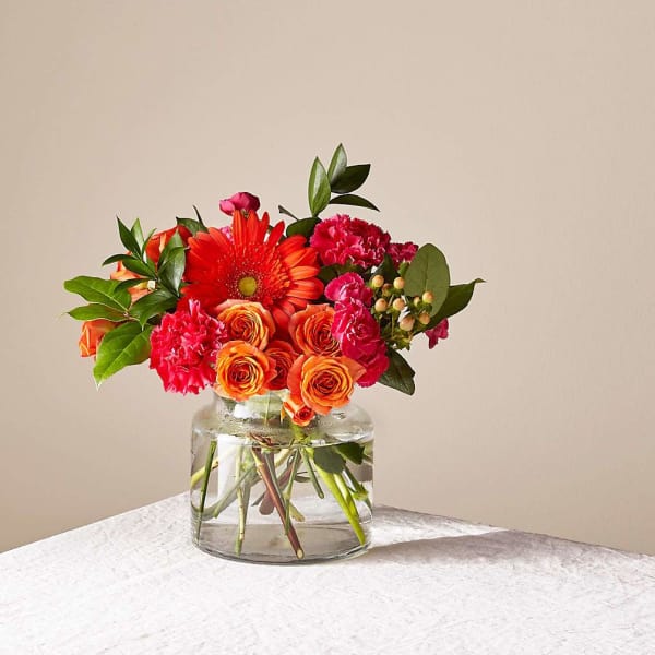 Bright orange and red bouquet in a clear glass vase