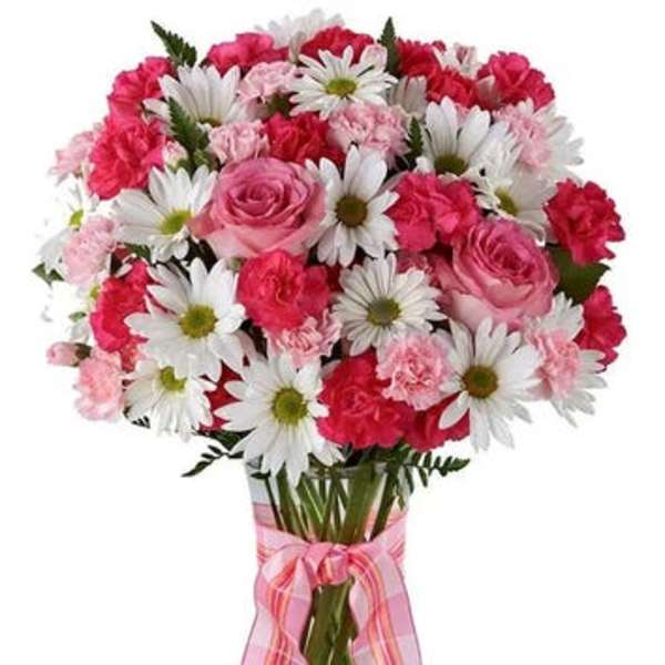 Pink and white bouquet of roses, carnations, and daisies in a glass vase