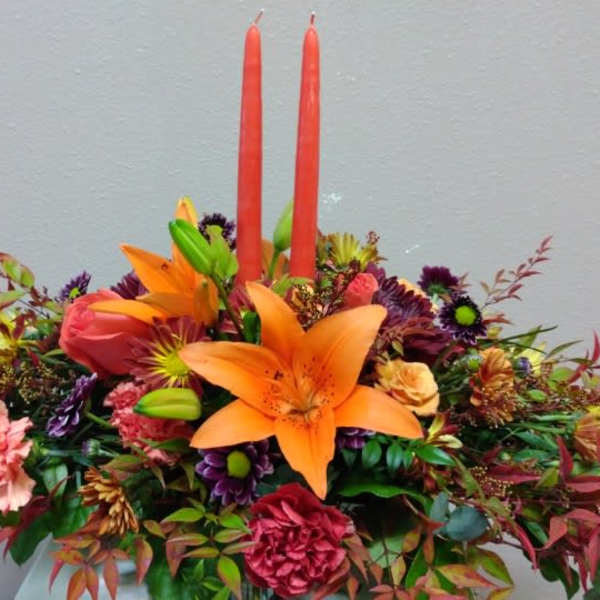 Bright floral arrangement with orange lilies and two red candles