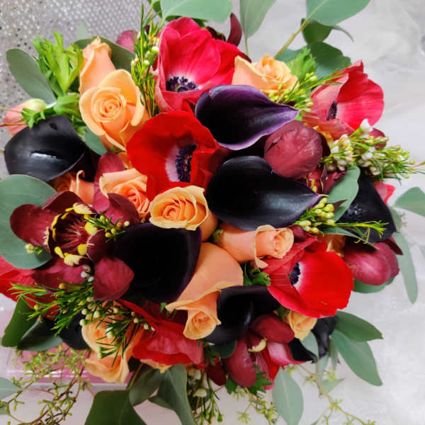Bouquet of red and peach flowers with dark calla lilies