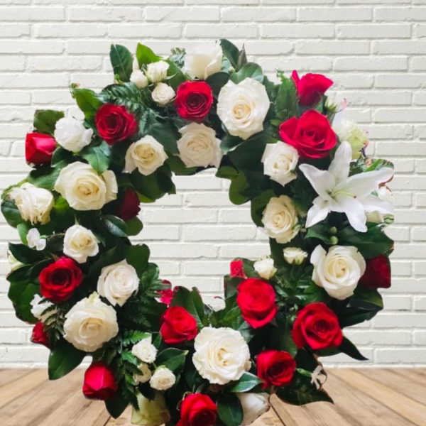 Circular wreath of red and white roses with a white lily