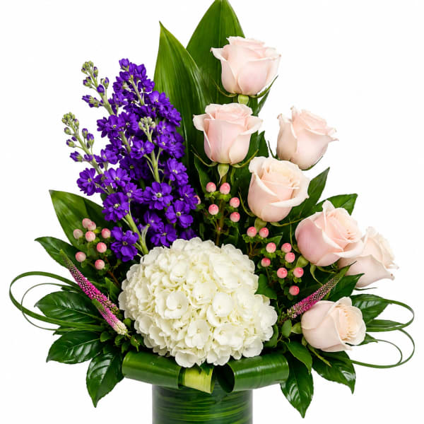 Pink roses and purple flowers in a green glass vase with white hydrangea
