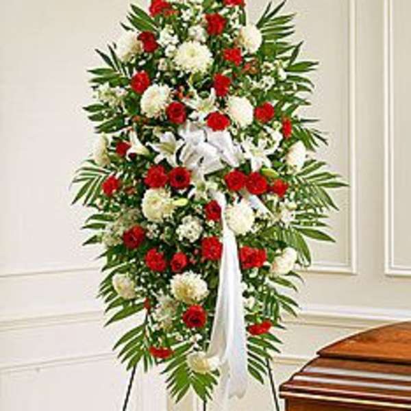 Tall standing spray of red and white flowers with a white ribbon on an easel