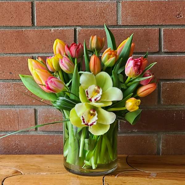 Bouquet of tulips and orchids in a glass vase