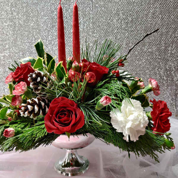 Christmas centerpiece with red roses, white carnations, and candles in a glass vase