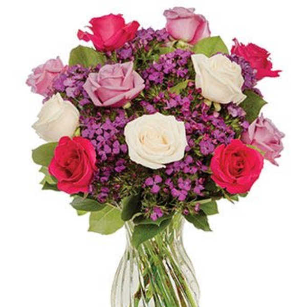 Bouquet of pink, white, and red roses in a clear glass vase