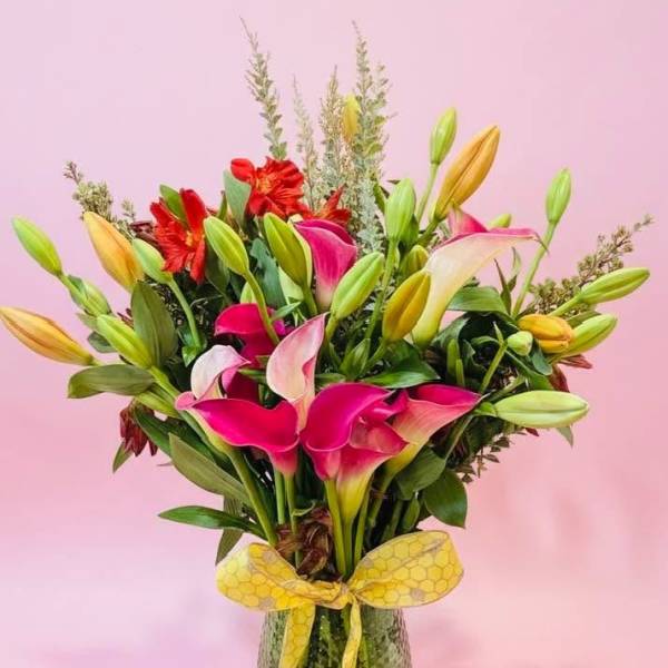 Bouquet of pink and white calla lilies with red flowers in a glass vase