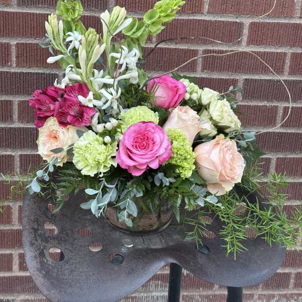 Mixed bouquet in a glass vase with pink, peach, white, and green flowers