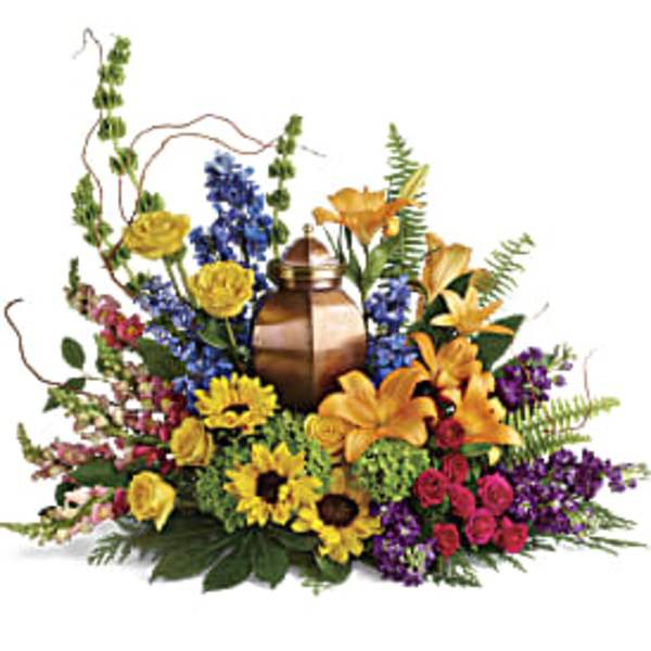 Colorful funeral urn arrangement with lilies, roses, and sunflowers