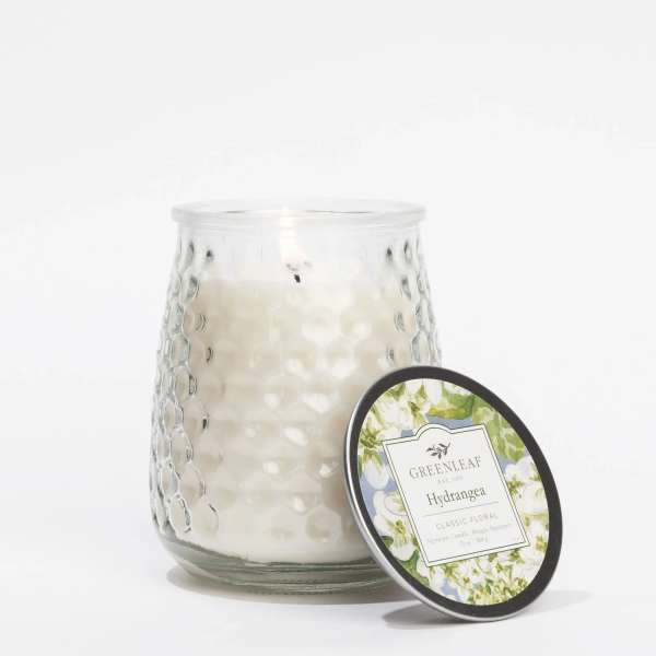 White candle in a textured glass jar with a matching lid