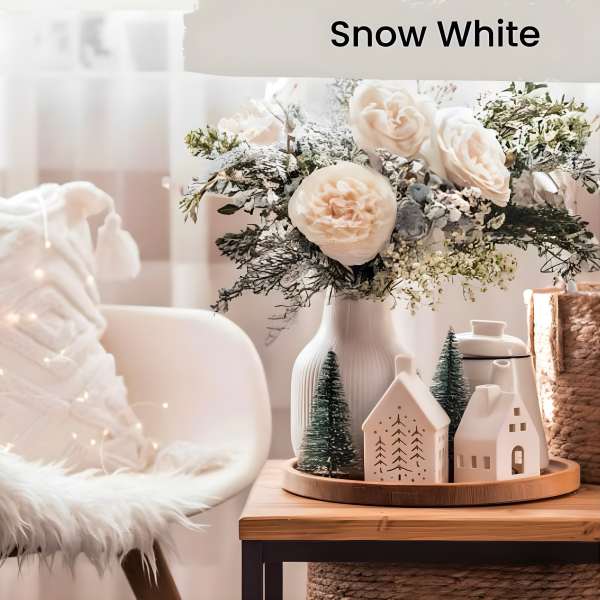 White rose arrangement in a ribbed vase with small decorative houses