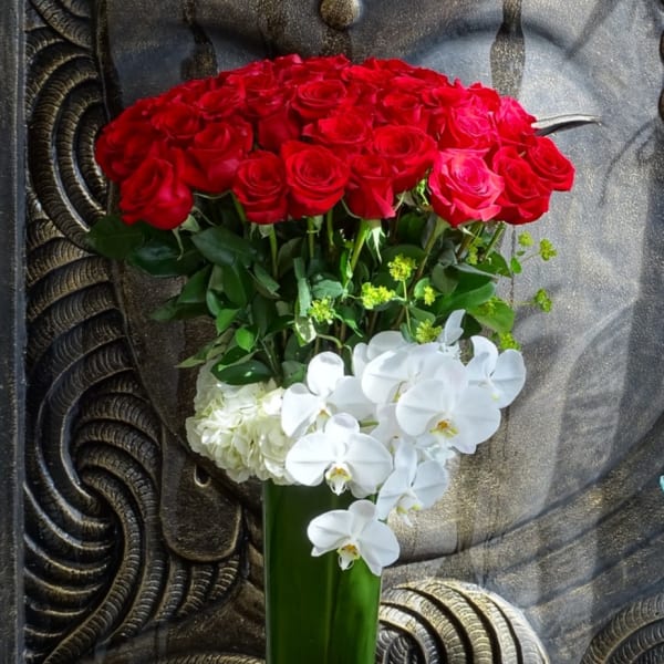 Red roses and white orchids in a tall green vase