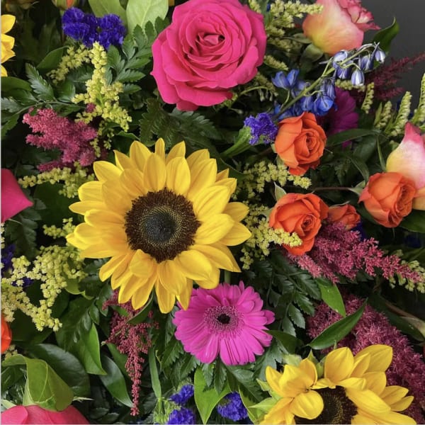 Mixed bouquet with sunflowers, roses, and a pink gerbera daisy