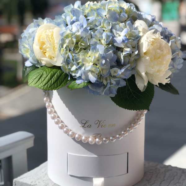 Blue hydrangeas and white peonies in a white hat box with pearl trim