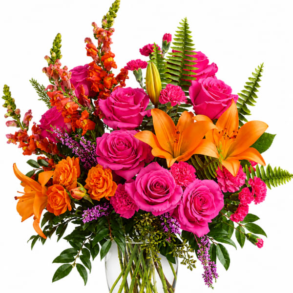 Bright mixed bouquet of pink roses, orange lilies, and orange snapdragons in a glass vase