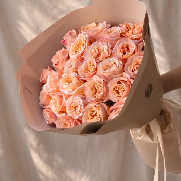 Bouquet of peach roses wrapped in beige paper
