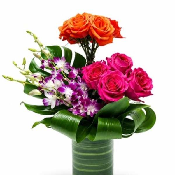 Bouquet of orange and pink roses with purple orchids in a glass vase