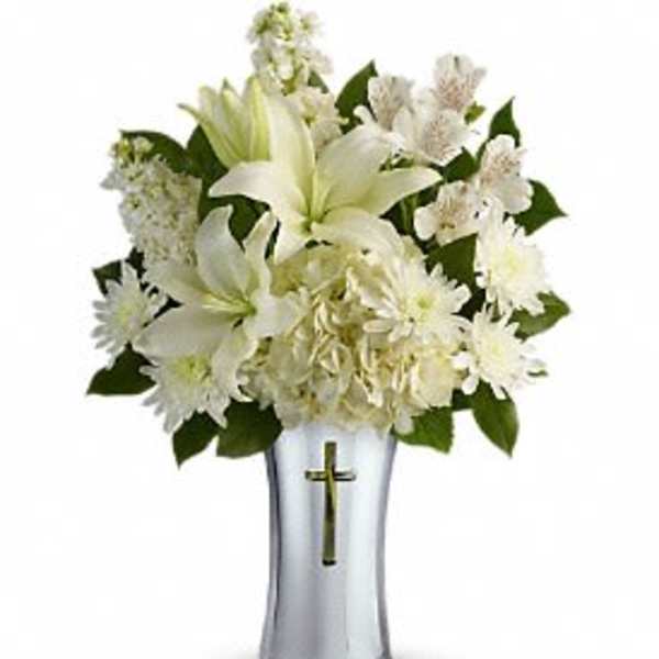 White lilies and daisies in a silver vase with a cross