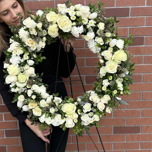 Large white floral wreath on a black stand