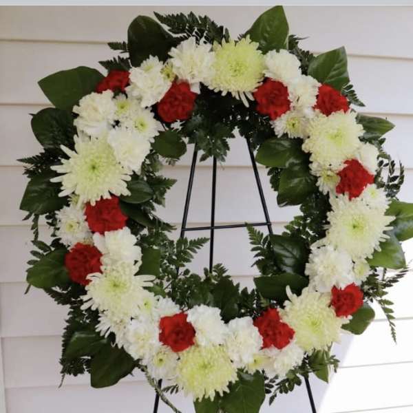 Red and white floral wreath on a black stand