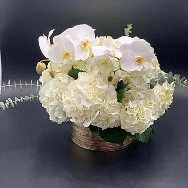 White orchids and hydrangeas in a low woven basket
