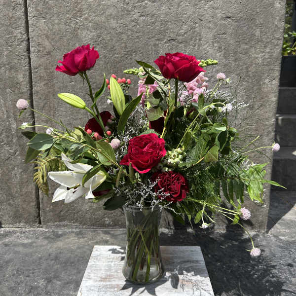 Mixed bouquet of red roses and white lilies in a clear glass vase